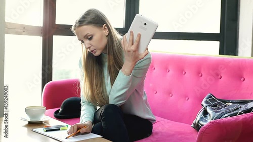 Girl studying in the cafe and checking notes with her friend while speaking on videocall
 photo