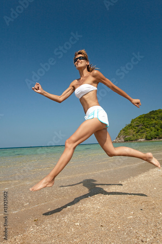 femme souriant qui saute sur une belle plage