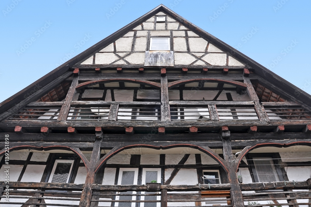 Obraz premium Looking up at historic half-timbered building made of dark wood with balconies and decorative elements. Tubingen, Baden-Wurttemberg, Germany.