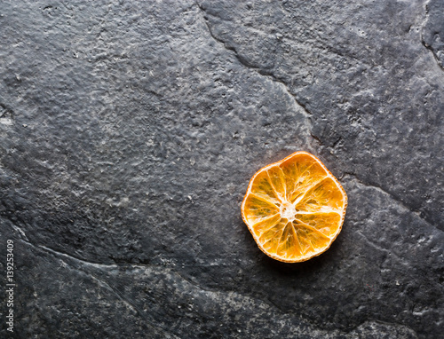 Dry slices of citrus fruits on a black slate background. photo