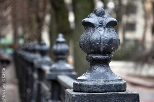 Vintage black metal fence with decorative elements in perspective. Selective focus.