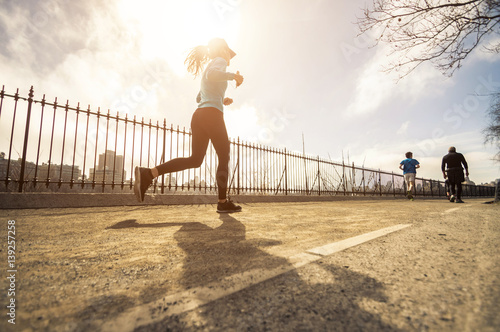 Young woman runner running on the road at morning photo