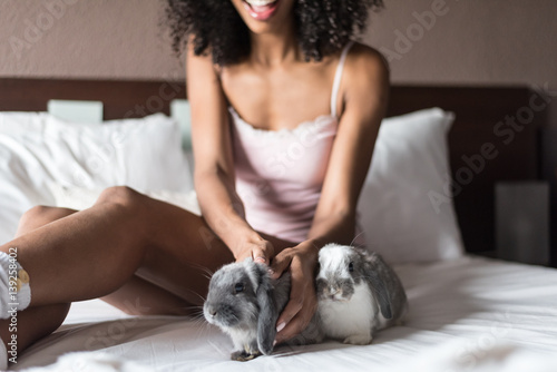 woman on bed playing with bunnies