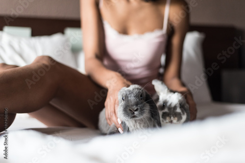 woman playing with bunnies on bed
