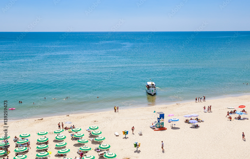 The Black Sea shore, blue clear water, beach with sand, umbrellas and sunbeds. Albena, Bulgaria