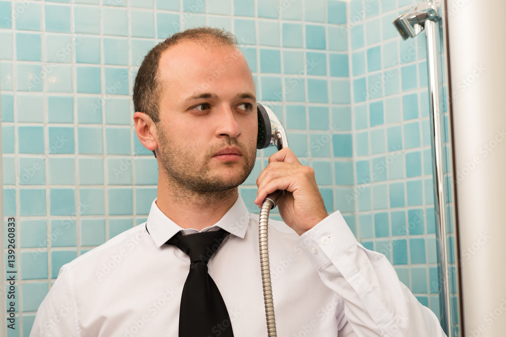 serious handsome business man standing in bathroom with shower in hand serious handsome business man standing in bathroom with shower in hand