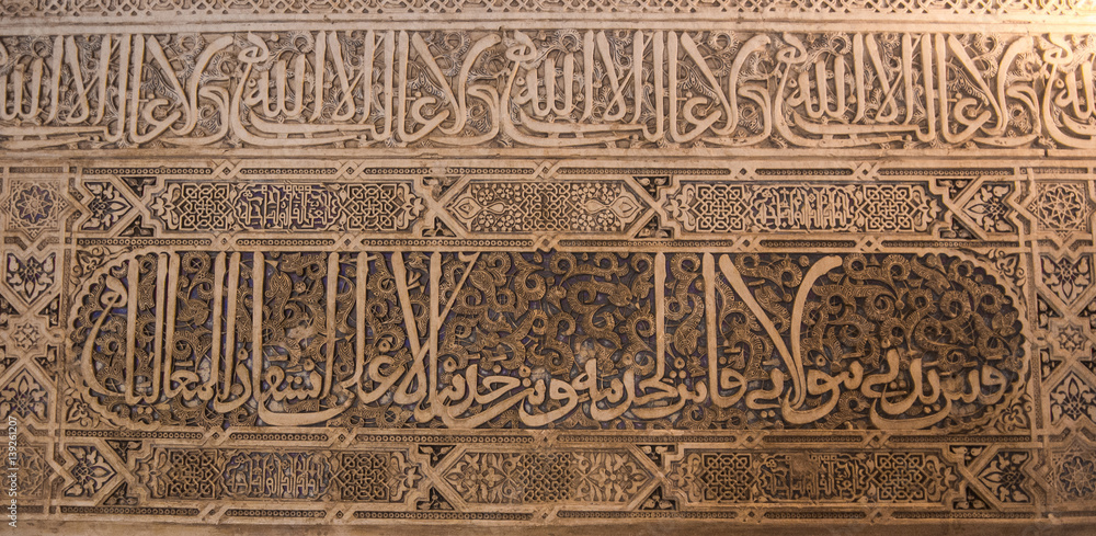 GRANADA, SPAIN - FEBRUARY 10, 2015: A close-up view to calligraphy decorated details of an archway at palace of Alhambra, Granada, Andalusia, Spain.