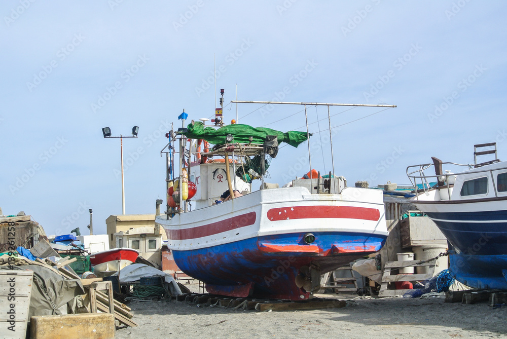 CABO DE GATA, SPAIN - FEBRUARY 9, 2016: Fishing boats at the shore of national park Cabo de Gata near Almeria (Andalusia, Spain) and sea waves on the background.