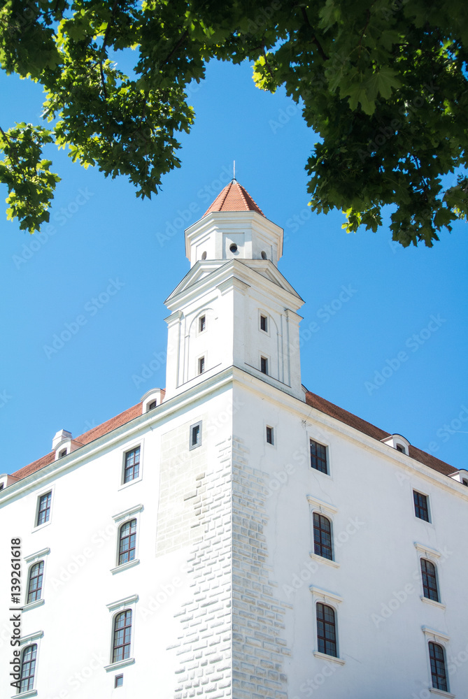 Close-up view to a tower of Bratislava castle and green maple leaves, Slovakia. Close-up view to a tower of Bratislava castle and green maple leaves, Slovakia.