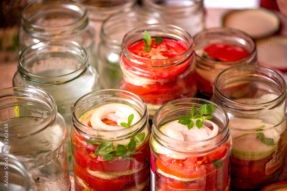 Canning fresh tomatoes with onions for winter in jelly marinade. A shot of basil leaves on top of a red ripe tomato slices and onion rings being put in jar.
Canning fresh tomatoes with onions for winter in jelly marinade. A shot of basil leaves on top of a red ripe tomato slices and onion rings being put in jar.