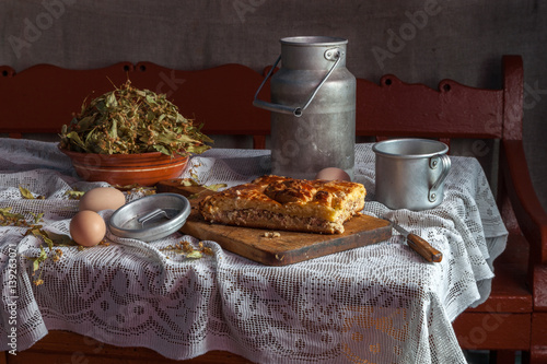Still life in a rustic style: aluminum dishes and pie on a wooden table.