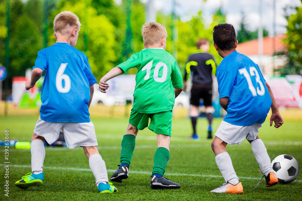Football Player Running with the Ball on the Pitch. Footballers Kicking Football Match on the Pitch. Young Teen Soccer Game. Youth Sport Background Football Player Running with the Ball on the Pitch. Footballers Kicking Football Match on the Pitch. Young Teen Soccer Game. Youth Sport Background