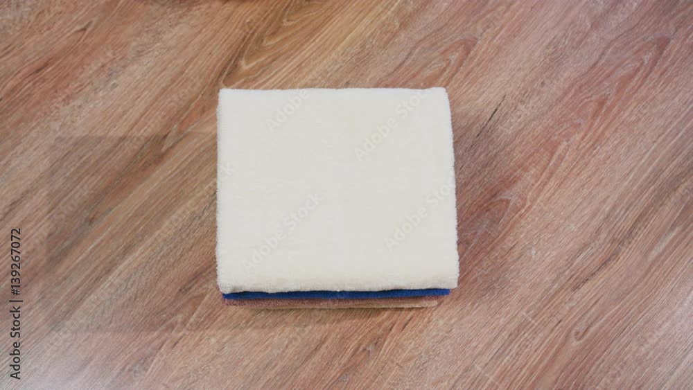 female hand taking a towel from the stack and puts it on a stack of towels lying on derevlany surface top view female hand taking a towel from the stack and puts it on a stack of towels lying on derevlany surface top view
