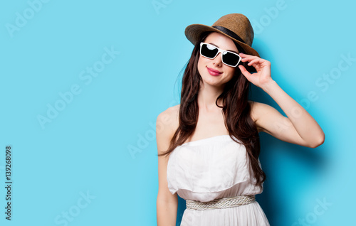 beautiful young woman in sunglasses standing in front of wonderful blue background
