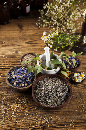 Herbs  berries and flowers with mortar  on wooden table background