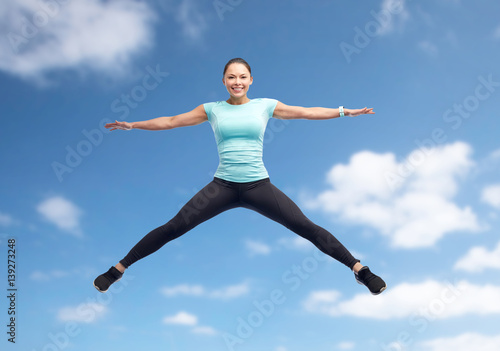 Fototapeta Naklejka Na Ścianę i Meble -  happy smiling sporty young woman jumping in air
