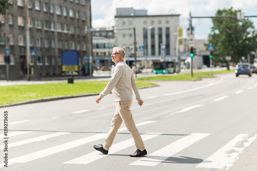 senior man walking along city crosswalk senior man walking along city crosswalk