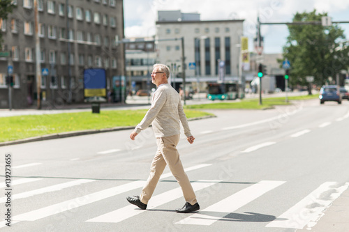Fototapeta senior man walking along city crosswalk
