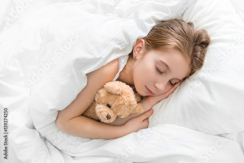 child hugging her teddy bear in sleep