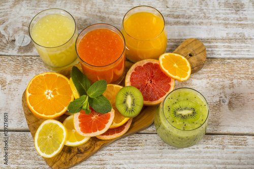 Fototapeta Naklejka Na Ścianę i Meble -  Citrus juices in glass and a slice of  lemon, grapefruit and  orange on wooden background .