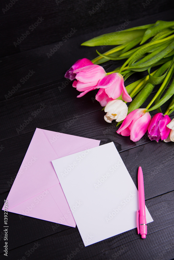 Bouquet of tender pink tulips and clear paper on black wooden background Bouquet of tender pink tulips and clear paper on black wooden background