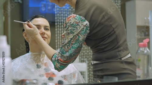 Young woman with hair in the paint, to eyebrow make-up sitting from the master image maker beauty salon ultra HD photo