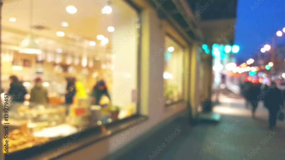 Blurred background cafe windows exterior with defocused lights with people going the street Blurred background cafe windows exterior with defocused lights with people going the street