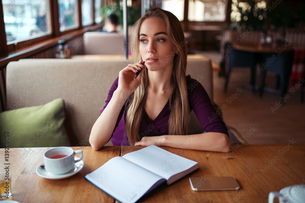 Female writing in notebook in restaurant. Female writing in notebook in restaurant.