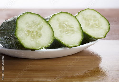 Fresh green cucumber in a salad before treatment lying on a plate photo