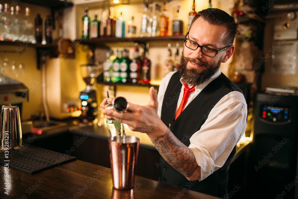 Bartender pouring alcohol beverage in metal glass