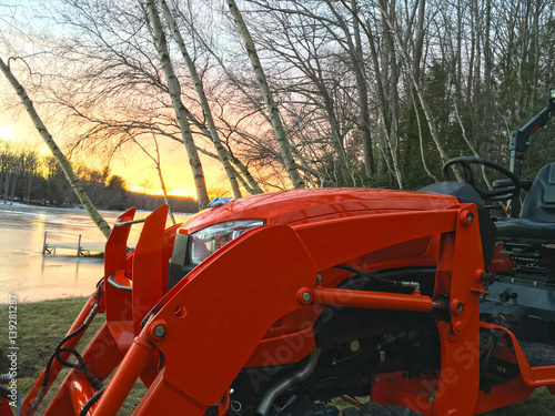 Tractor loader in sunset with lake