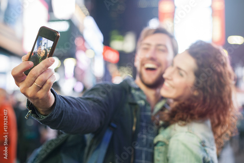 Young couple taking selfie in Times Square, New York City, New York, USA