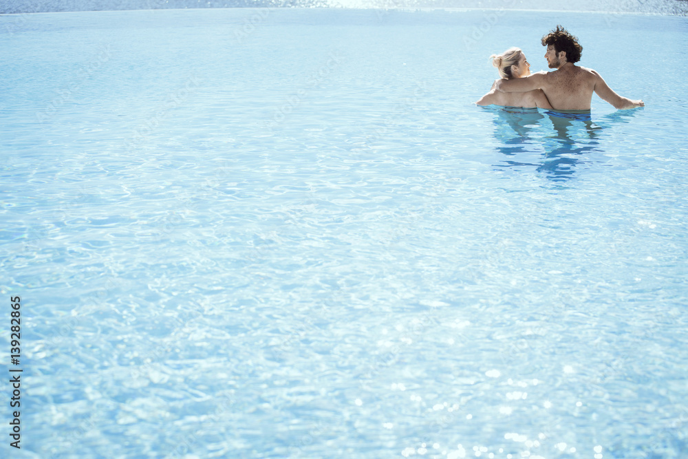 Couple relaxing together in pool, rear view Couple relaxing together in pool, rear view