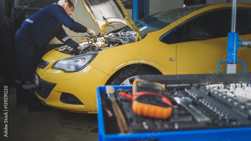 Fototapeta Naklejka Na Ścianę i Meble -  Mechanic repairs a car - unscrews detail of automobile - garage service