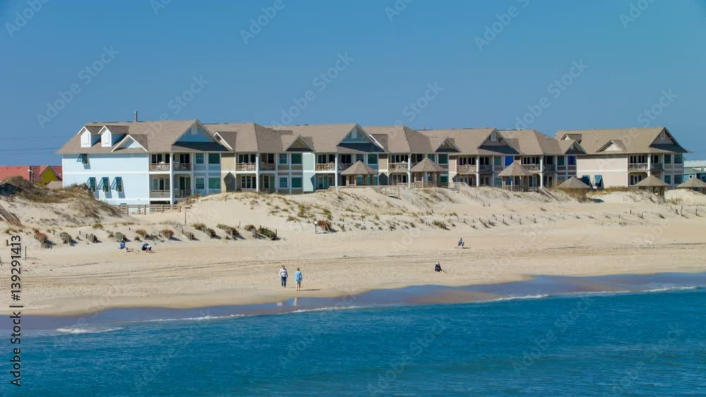 Outer Banks Nags Head NC Beach with Condos and People Walking on Sand alongside Atlantic Ocean Water Waves on an Idyllic Sunny Day in North Carolina