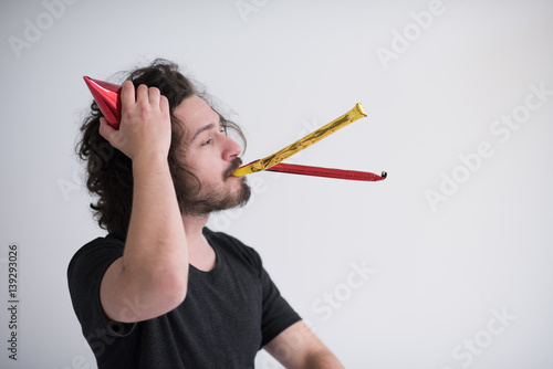 Portrait of a man in party hat blowing in whistle