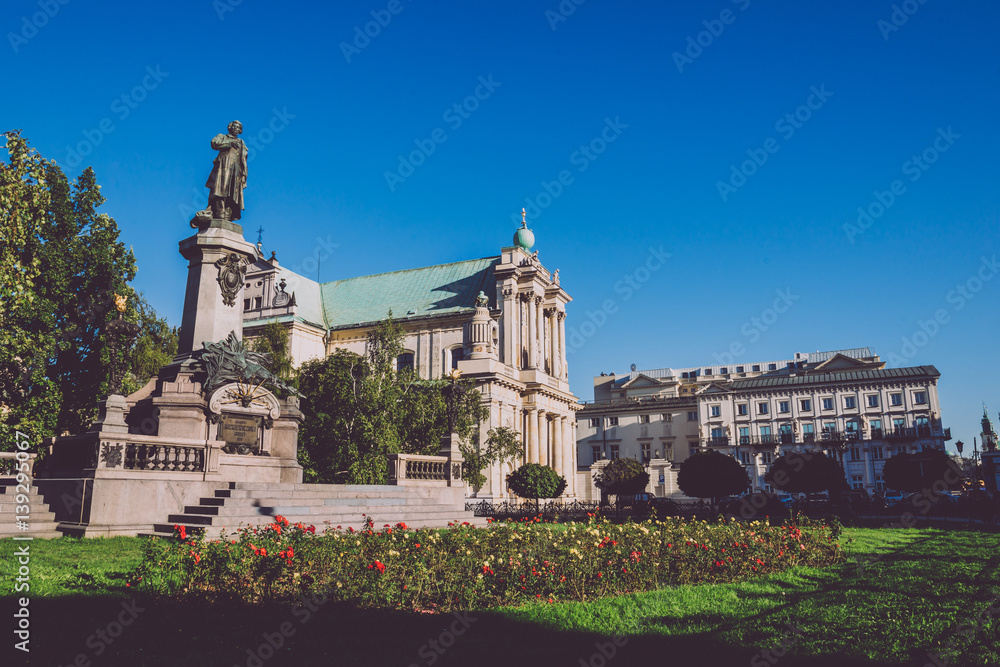 Adam Mickiewicz Monument and Carmelite Church in Warsaw, Poland. Church of the Assumption of the Virgin Mary and of St. Joseph and famous polish and belarus poet statue at the Skwer Adama Mickiewicza.