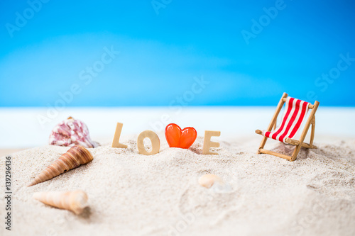 valentine decoration with love wooden text and beach chair on white sand beach with tropical blue sea and clear blue sky Image For Love Valentine Day or summer   vacation Concept.