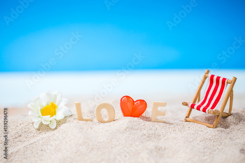 valentine decoration with love wooden text and beach chair on white sand beach with tropical blue sea and clear blue sky,Image For Love Valentine Day or summer vacation Concept.