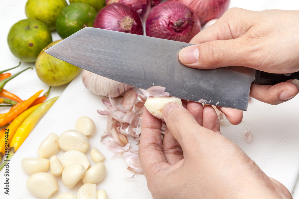 Peeling off the garlic skin, prepare for cooking with some Indian shallots, limes and chili in the kitchen