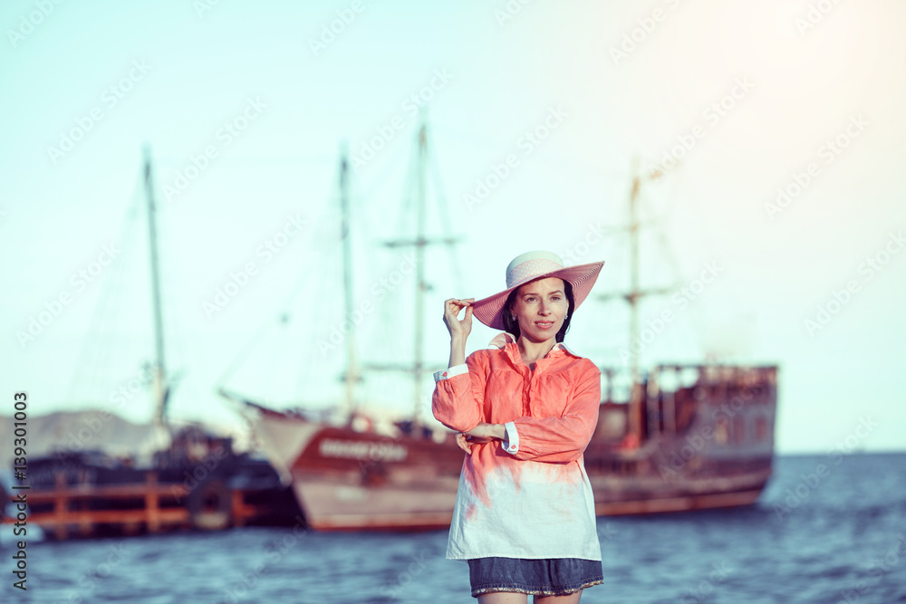 Obraz premium Beautiful girl, brunette on the pier. Yachts, boats, fishing boats in the background.