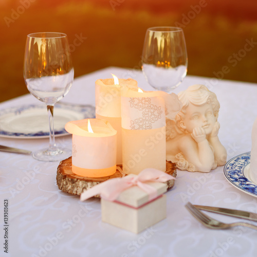 Table decorated with candles and angels for wedding or romantic dinner. Gift box with wedding rings, proposal or marriage concept