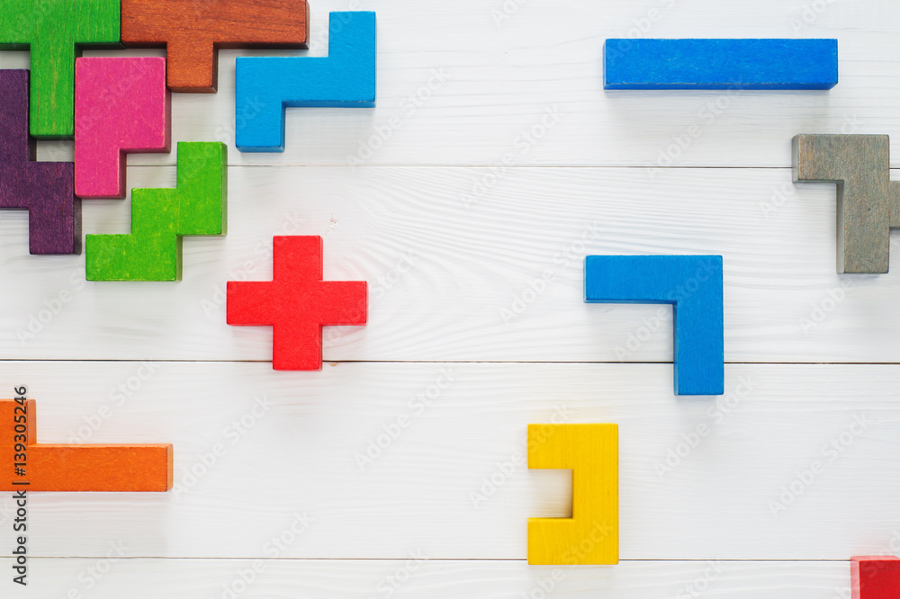 Obraz premium Concept of creative, logical thinking. Different colorful shapes wooden blocks on white wooden background, flat lay, copy space. Geometric shapes in different colors, top view. Abstract Background.