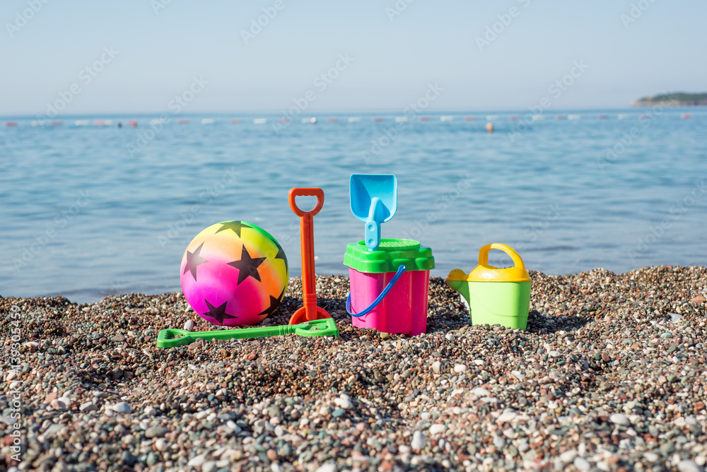 Baby beach equipment, toys on a pebble beach Baby beach equipment, toys on a pebble beach