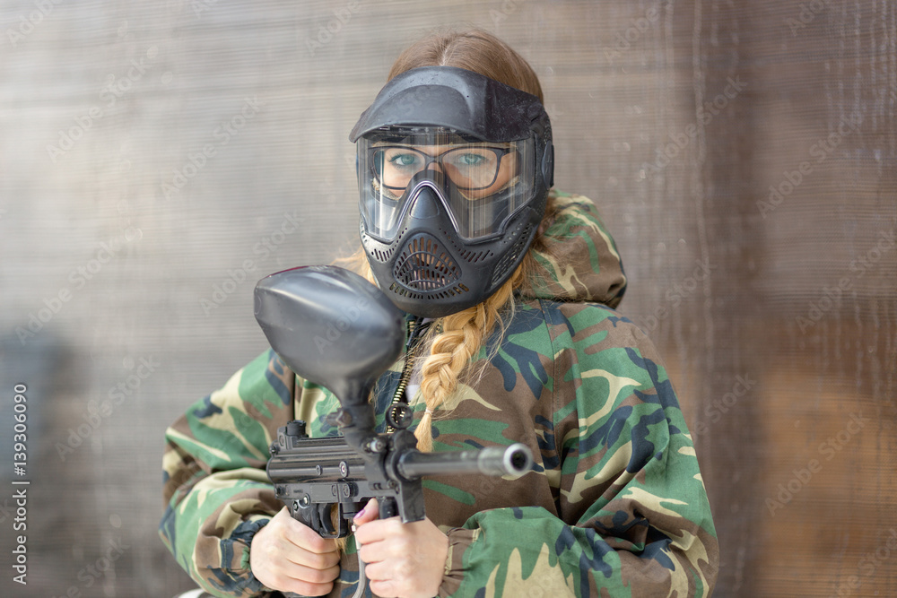 Fototapeta premium girl playing paintball in overalls with a gun.