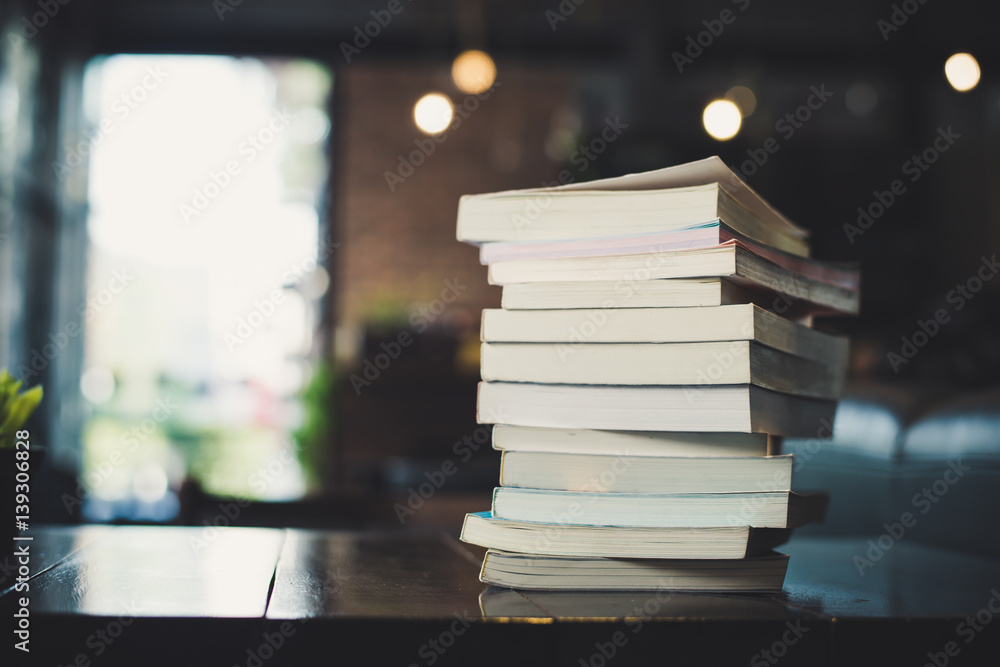 Fototapeta premium piles of books on table over blurred library background.