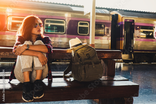 young woman traveler wearing backpack waiting railway at train station, Summer holiday and travel concept photo