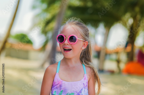 Portrait of a cute girl wearing sunglasses in the tropics on the cellular. vacation concept.