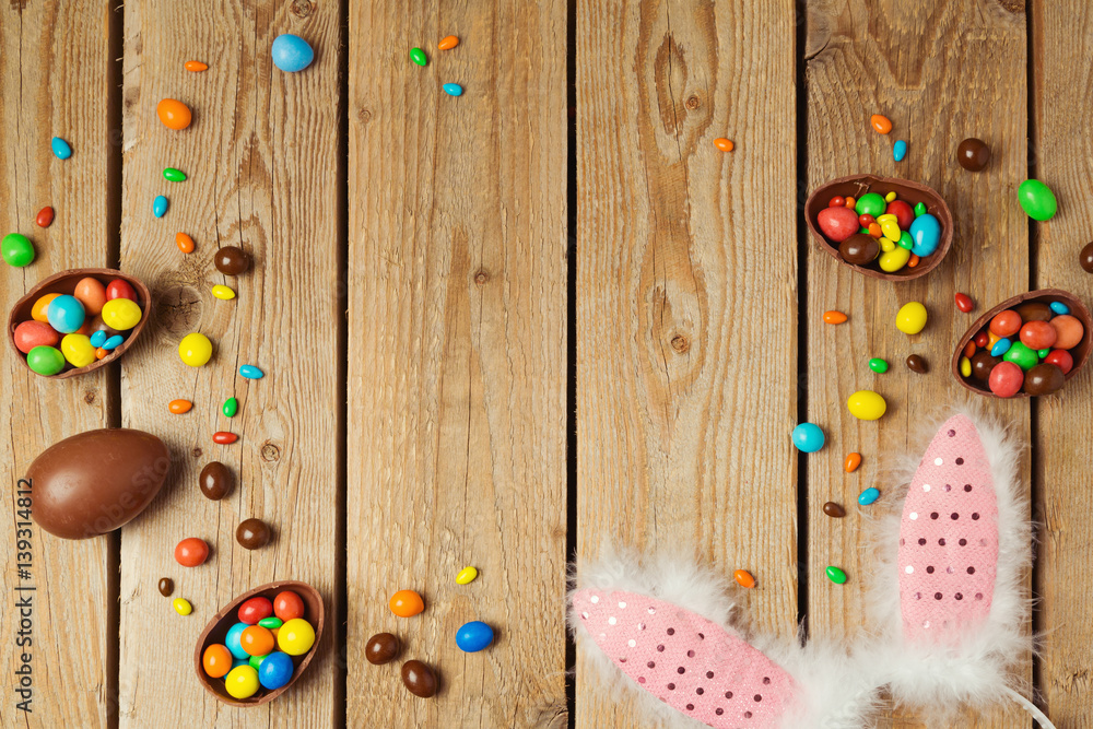 Easter holiday concept with chocolate eggs and bunny ears on wooden background. Top view from above with copy space Easter holiday concept with chocolate eggs and bunny ears on wooden background. Top view from above with copy space