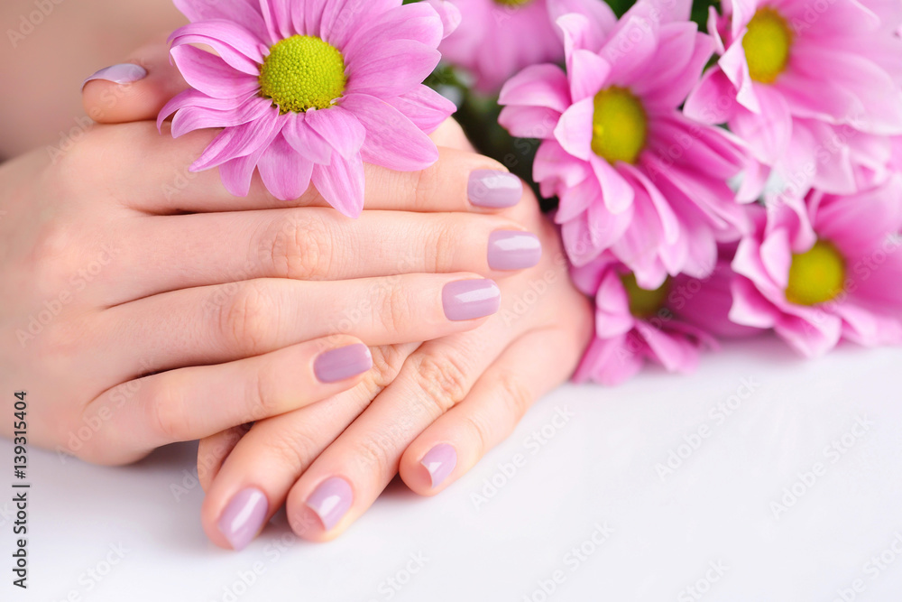 Hands of a woman with pink manicure on nails and pink flowers Hands of a woman with pink manicure on nails and pink flowers